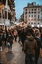 A vibrant street filled with people in the evening, showcasing urban life and city architecture.